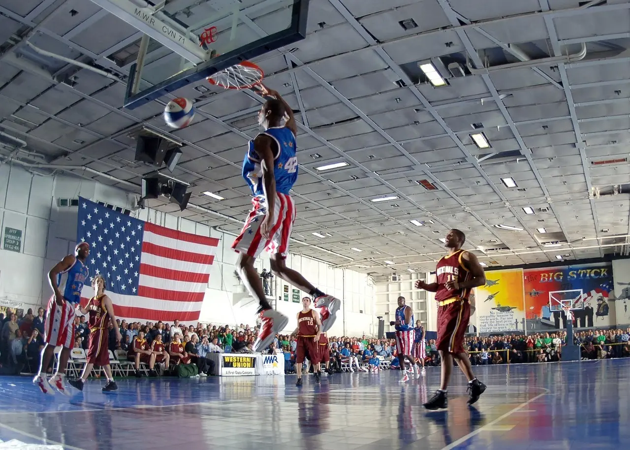 Basketballspiller der dunker i en kamp foran publikum