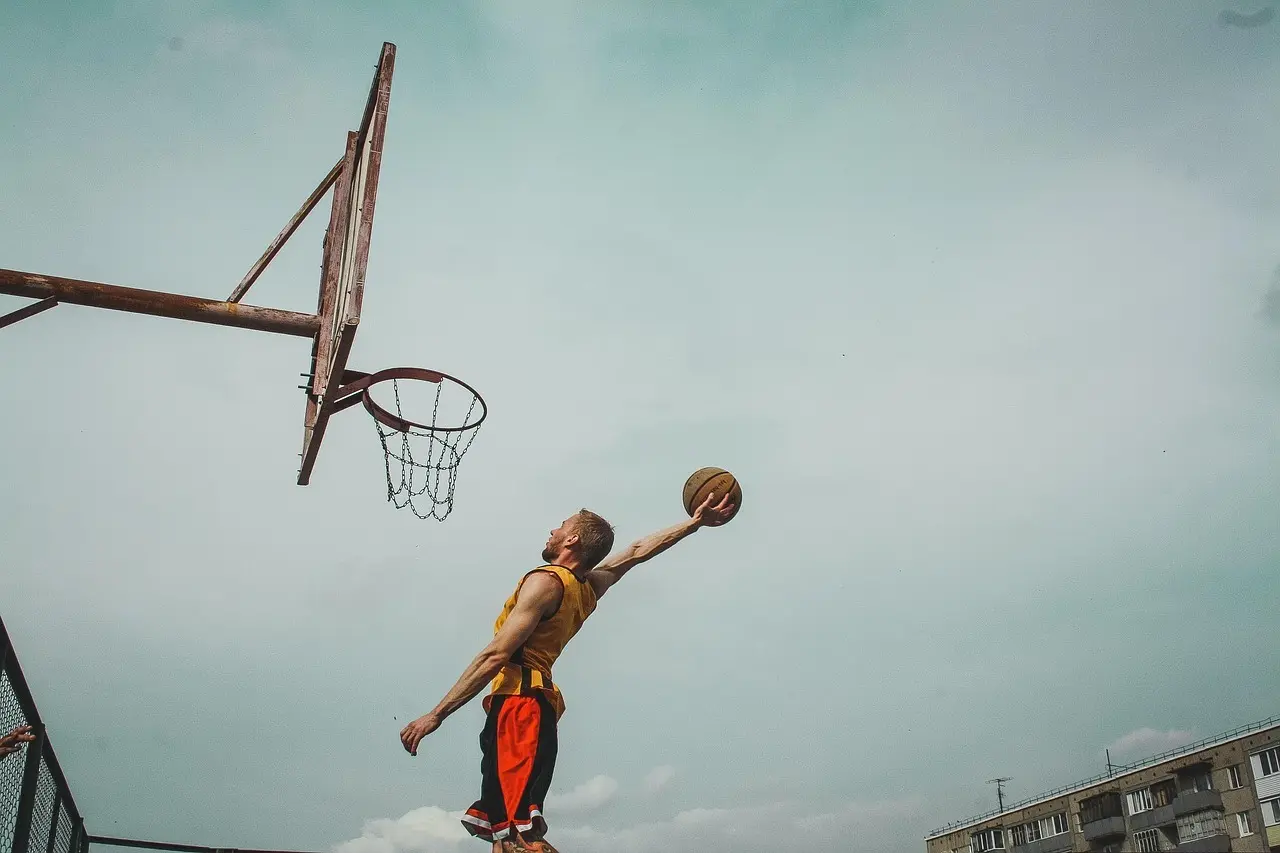 Basketballspiller der dunker ved en udendørs kurv